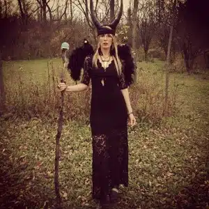 Woman in black costume with horns outdoors.
