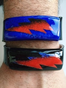 Two glass bracelets with red and blue lightning bolt designs.