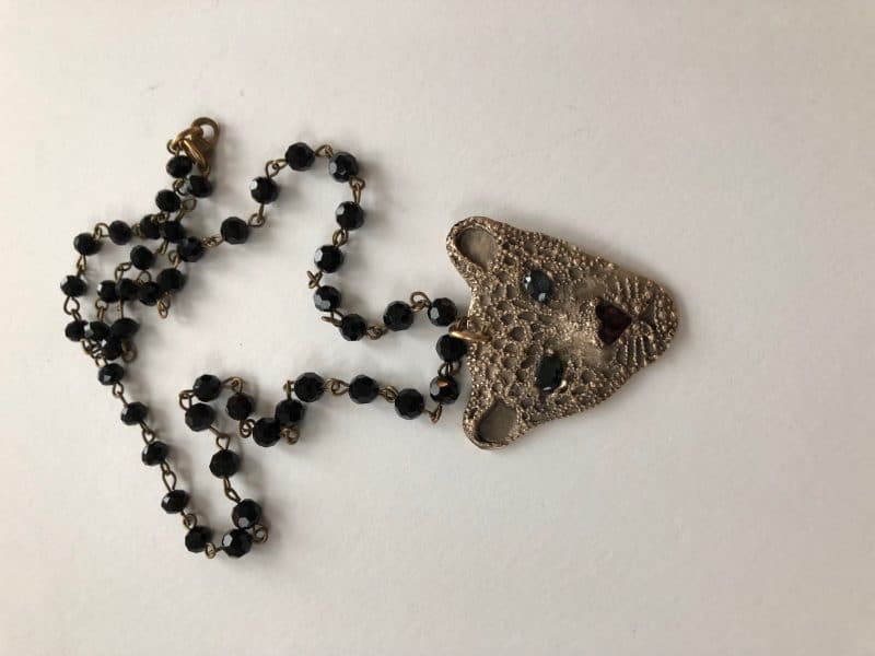 A black beaded necklace with a silver panther-shaped pendant adorned with colored stones.