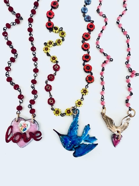 Three colorful beaded necklaces with unique pendants.