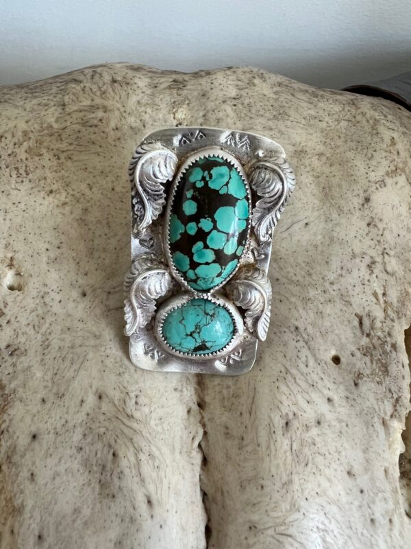 Intricately designed silver jewelry with turquoise stones on a textured surface.