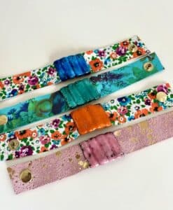 Colorful floral leather bracelets with textured central clasps in blue, teal, orange, and pink.