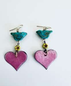 Colorful earrings with blue birds, yellow flowers, and pink hearts.