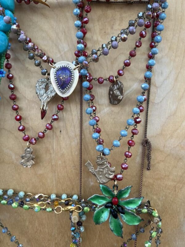 Colorful beaded necklaces with various pendants hanging on a wooden surface.