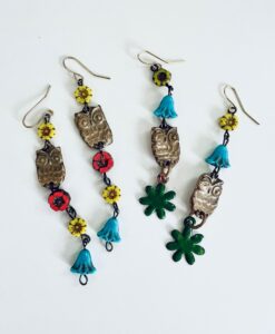 Colorful owl earrings with floral and leaf designs.
