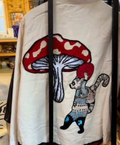 A fabric with a cat carrying a red mushroom design.