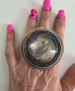 Large round ring with a stone on a hand with bright pink nails.