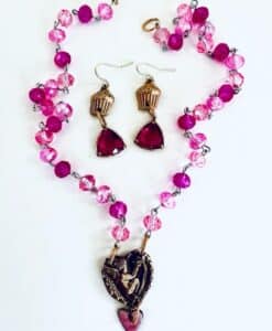 Pink beaded necklace and matching earrings with heart-shaped pendants.