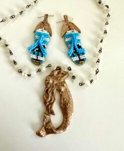 Colorful beaded earrings and a bronze mermaid pendant with a white beaded necklace.