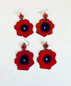Four red flower-shaped earrings with black centers displayed on a white background.
