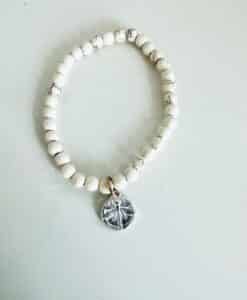 Beaded bracelet with a dragonfly charm on a white surface.