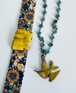 A vibrant floral watch strap and a turquoise-beaded necklace with a yellow bird pendant.