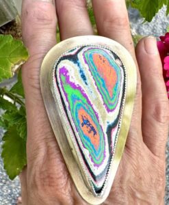 Colorful, polished stone with vibrant layers held in hand.