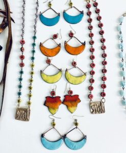 Colorful handmade earrings and necklaces with leaf and geometric designs.