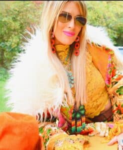 Woman in vibrant, eclectic autumn outfit with sunglasses and colorful accessories.