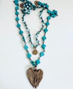 A turquoise rosary with a winged pendant and a small medallion.