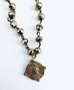 Close-up of a metallic beaded necklace with a round pendant.