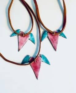Three handmade necklaces with pink and turquoise bird-shaped pendants on brown cords.