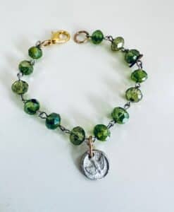 Green beaded bracelet with a silver owl charm and gold clasp.