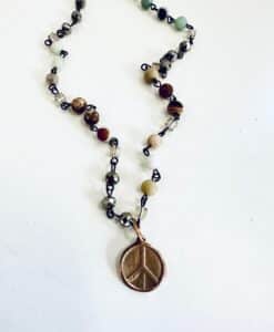 Necklace with a peace sign pendant and multicolored beads on a white background.