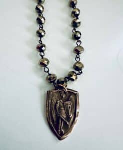 A necklace with a medieval knight pendant on a beaded chain.