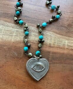 Heart-shaped pendant necklace with an eye design and turquoise beads.