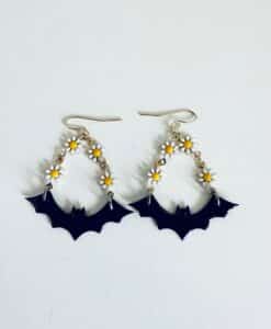 Earrings featuring black bats and small white daisies with yellow centers.