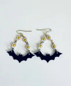 Earrings featuring black bats and small white daisies with yellow centers.