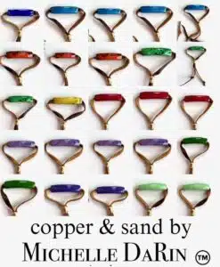 Rows of colorful gemstone rings with copper bands arranged neatly.